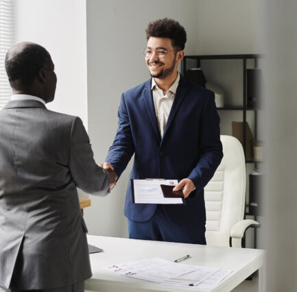 Specialist of visa center congratulating man of getting visa, they standing and shaking hands