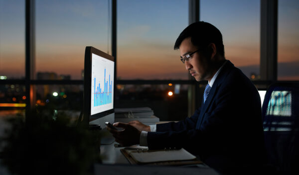 Serious Vietnamese businessman working on financial report in dark office